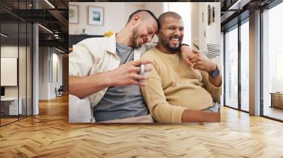 Laughing, relax and a gay couple on the sofa with coffee, conversation or love in a house. Happy, together and lgbt men on the living room couch for a funny story, communication or speaking with tea Wall mural