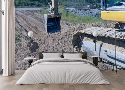 the process of leveling sand with an excavator bucket during the construction of a dirt road Wall mural