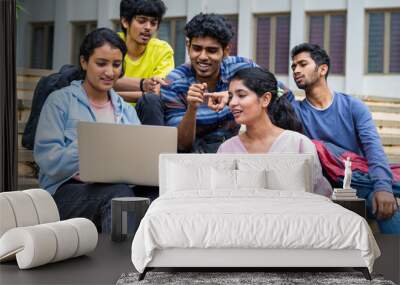 Group of happy students checking results on laptop while sitting on college campus - concept of education, technology and project work discussion. Wall mural