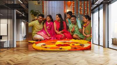 Group of Indian joint family members taking selife in front of decorated diwali rangoli at home - concept of festival gathering, reunion and festival celebration Wall mural