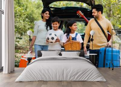 Happy indian fmaily with kids with picnic basket and travel lagguage at destination - concept safe car travel, transportation and vacation or holidays. Wall mural