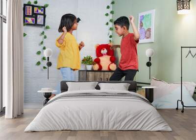 Happy smiling sibling kids dancing by jumping on bed at home - concept of playful childhood, bonding and relationship. Wall mural