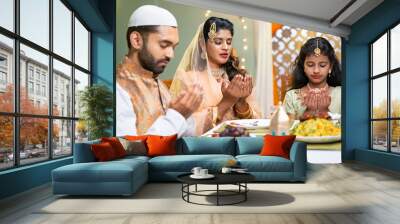 Indian Muslim family with kid praying at ramadan iftar dinner before eating at home - concept of traditional festival culture, rmzan kareem and family bonding Wall mural