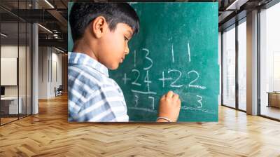 intelligent elementary school kid solving maths problem on chalkboard at classroom -concept of talented, brilliant student and education. Wall mural