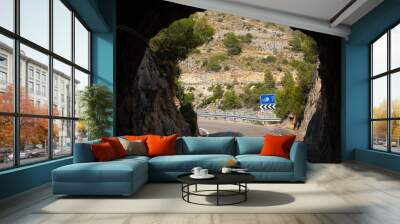 A blue white traffic sign indicating that the driver should turn off the lights after exiting the tunnel. Behind the tunnel is a bridge on a reservoir near the Spanish city of Albacete. Wall mural