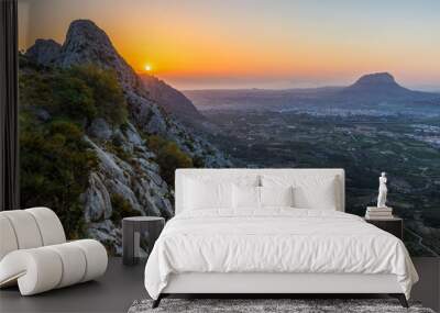 View from mountain Segaria in the back country to the spanish coastal city Denia at sunrise. A romantic vision in the early morning. The sun rises over the Mediterranean. Wall mural