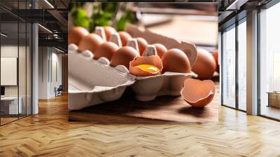 A cardboard box full of fresh chicken eggs with yolk in broken egg on the kitchen counter Wall mural