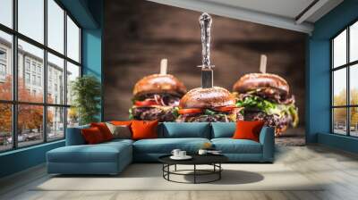 Assortment of three various burgers ready to be plated, with a dark wooden background Wall mural