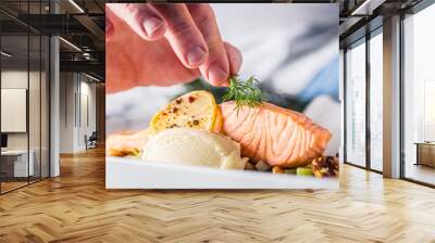 Chef in hotel or restaurant kitchen cooking, only hands. Prepared salmon steak with dill decoration Wall mural