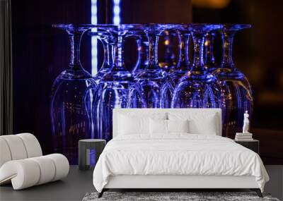 Clean wine glasses in the night bar glowing with neon colors Wall mural