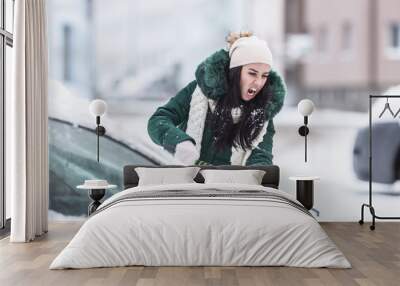 Clearing snow from the car on a winter day as a hard morning work after the snowstorm Wall mural