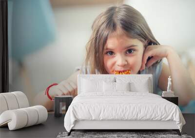 Cute little kid girl eating spaghetti bolognese at home Wall mural