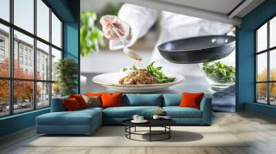 Female cook finishing food with sauce on counter in restaurant or hotel kitchen. The chef prepares the food just before taking it to the restaurant Wall mural