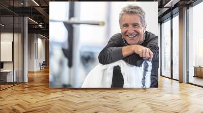 Fit in his sixties, man rests on a towel smiling inside the gym Wall mural