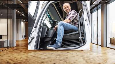 Happy and confident truck driver sits in his working cab with door open Wall mural