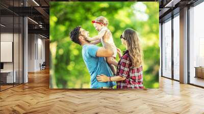 Happy family, father, mother and daughter are playing in the park and enjoying a sunny summer day Wall mural