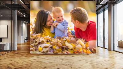 Happy family in autumn park playing with leaves. Wall mural