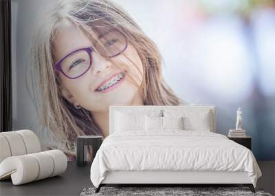 Happy smiling girl with dental braces and glasses. Young cute caucasian blond girl wearing teeth braces and glasses Wall mural