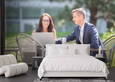 Office male and female colleagues discuss work over an open laptop and a takeaway coffee cup outdoors Wall mural