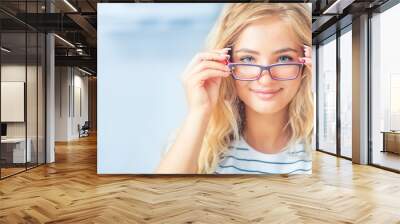 Portrait of young woman holding glasses and looking at camera. Wall mural