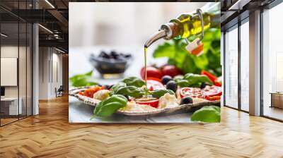 Pouring olive oil on caprese salad. Healthy italian or mediterranean meal Wall mural