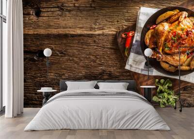 Roasted chicken and american potatoes with chili peppers and herbs - Top of view Wall mural