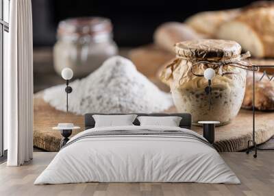 Rye sourdough ripened in a jar together with flour on a cutting board Wall mural