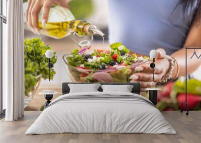 The final preparation of a healthy salad and at the end the woman pours olive oil Wall mural