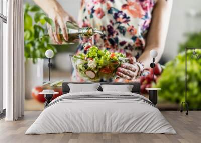 The final preparation of a healthy salad and at the end the woman pours olive oil Wall mural