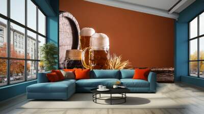 Three glasses with draft beer in front of a wooden barrel. Decoration of barley ears and fresh hops Wall mural