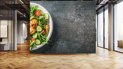 Top view of a healthy chicken salad in a white plate placed on the left half of the black rustic surface Wall mural