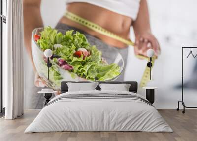 Woman holding bowl from salad and measure tape. Wall mural