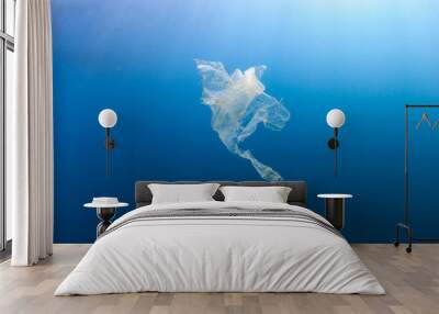 A shredded, discarded plastic bag floating underwater in a tropical ocean creating a hazard to marine life Wall mural