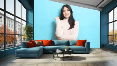 Beautiful girl in a warm cozy sweater on a colored background. Wall mural