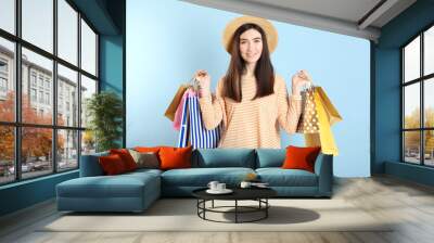 Beautiful young girl with paper bags for shopping on a colored background Wall mural