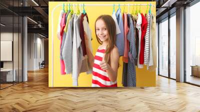 cute cheerful little girl chooses clothes with floor hangers. children's clothing, children's shoppi Wall mural