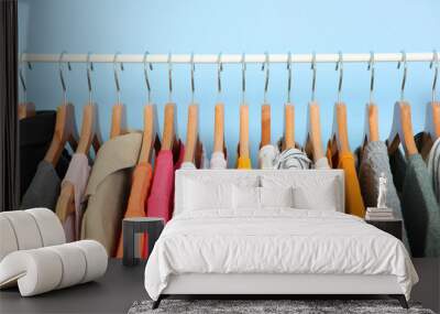 fashionable clothes on hangers on a wardrobe rack on a colored background. Wall mural