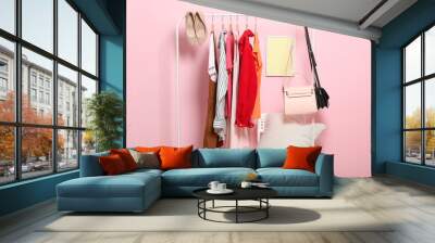 fashionable clothes on hangers on a wardrobe rack on a colored background. Wall mural