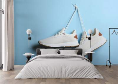 Modern trendy sneakers hang on laces on a colored background. Casual shoes, sports shoes. Place to insert text. Wall mural