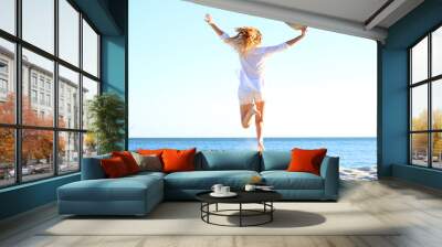 the girl is jumping against the sea. Wall mural