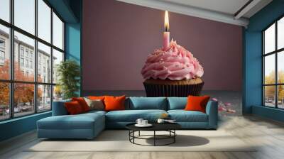 A pink cupcake with a lit candle on top Wall mural