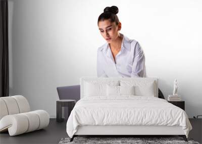 A businesswoman leaning over a table, working on a laptop with a coffee cup and notebook nearby, isolated on a white background, showcasing a concept of professionalism Wall mural