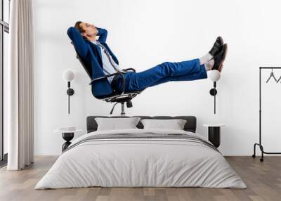 A man in a blue suit relaxing in an office chair, isolated on a white background, representing the concept of leisure or break time at work Wall mural