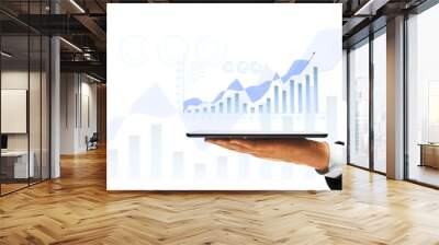 A person's hand holding a tablet with a digital graph, overlaid on a white background with financial symbols, symbolizing business growth Wall mural