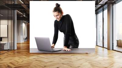 A smiling woman standing at a table with a laptop, isolated on a white background, depicting a modern professional or businesswoman Wall mural