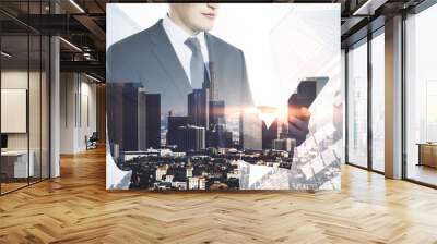 Attractive young european businessman using tablet on abstract bright city background. Success, technology and communication concept. Double exposure. Wall mural