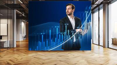 Attractive young european businesswoman using laptop with growing business chart hologram on blurry blue grid background. Corporate future growth plan. Wall mural