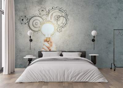 Businessman hand holding lamp with drawing cogs Wall mural