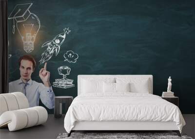 Businessman pointing up with education-related sketches on chalkboard background. Wall mural