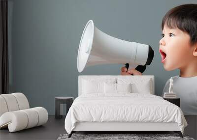 Child holding a megaphone and shouting on a grey background. Wall mural